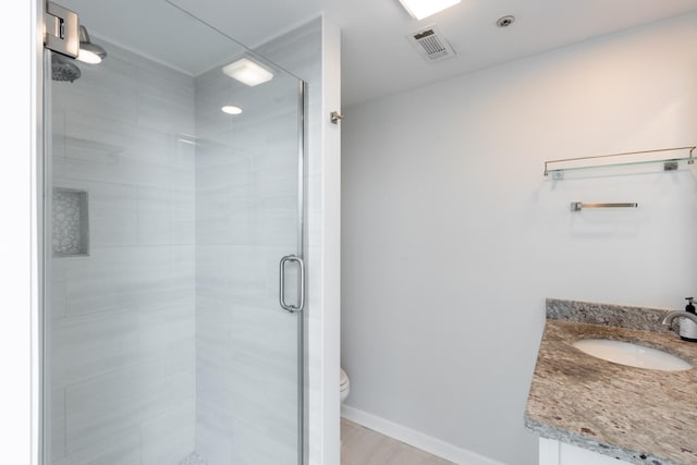 full bathroom featuring toilet, vanity, visible vents, baseboards, and a shower stall