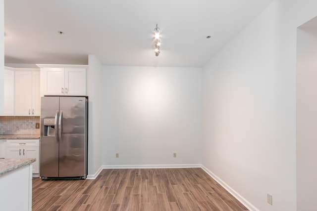 kitchen with backsplash, stainless steel refrigerator with ice dispenser, wood finished floors, and white cabinets