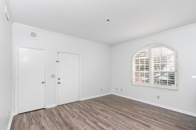 empty room with ornamental molding, wood finished floors, and baseboards