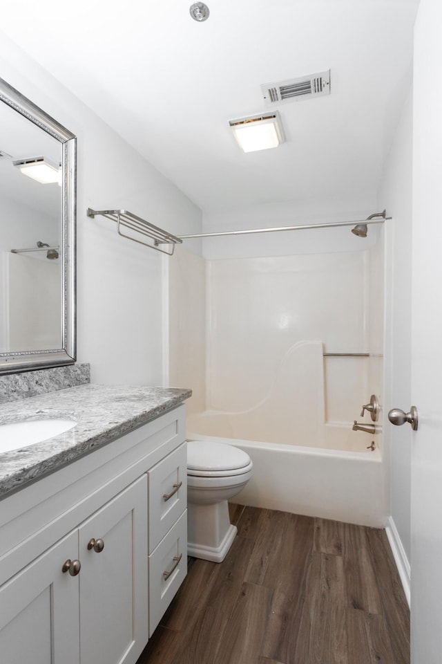 bathroom with shower / tub combination, toilet, wood finished floors, vanity, and visible vents