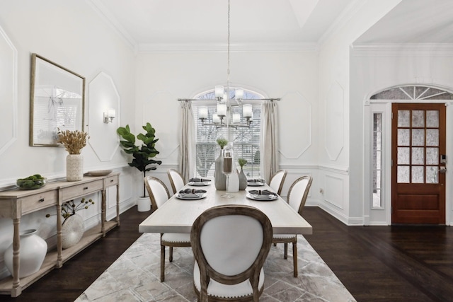 dining area with crown molding, a chandelier, a decorative wall, and wood finished floors