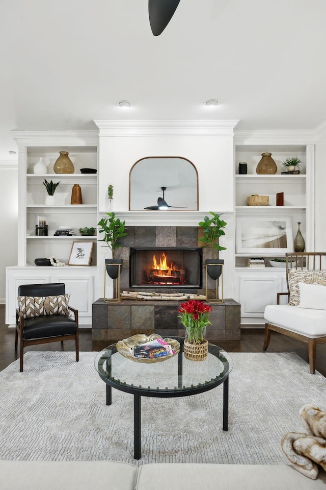 interior space featuring crown molding, wood finished floors, a ceiling fan, and a tile fireplace