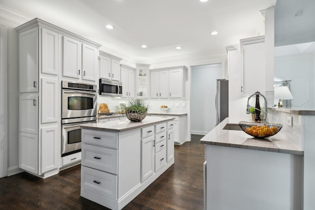 kitchen with appliances with stainless steel finishes, dark wood-style flooring, white cabinets, and backsplash