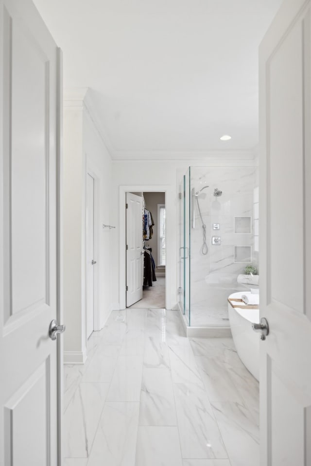 bathroom with marble finish floor, ornamental molding, a freestanding tub, and a stall shower