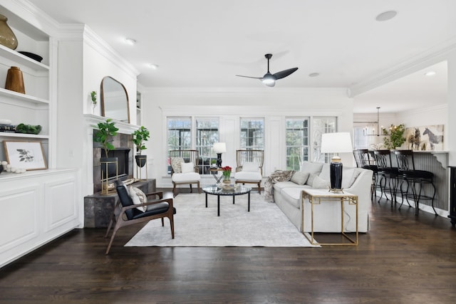 living area with a wealth of natural light, built in shelves, dark wood-style floors, and a tiled fireplace