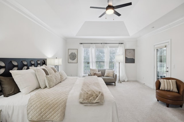 carpeted bedroom featuring a tray ceiling, crown molding, baseboards, and ceiling fan