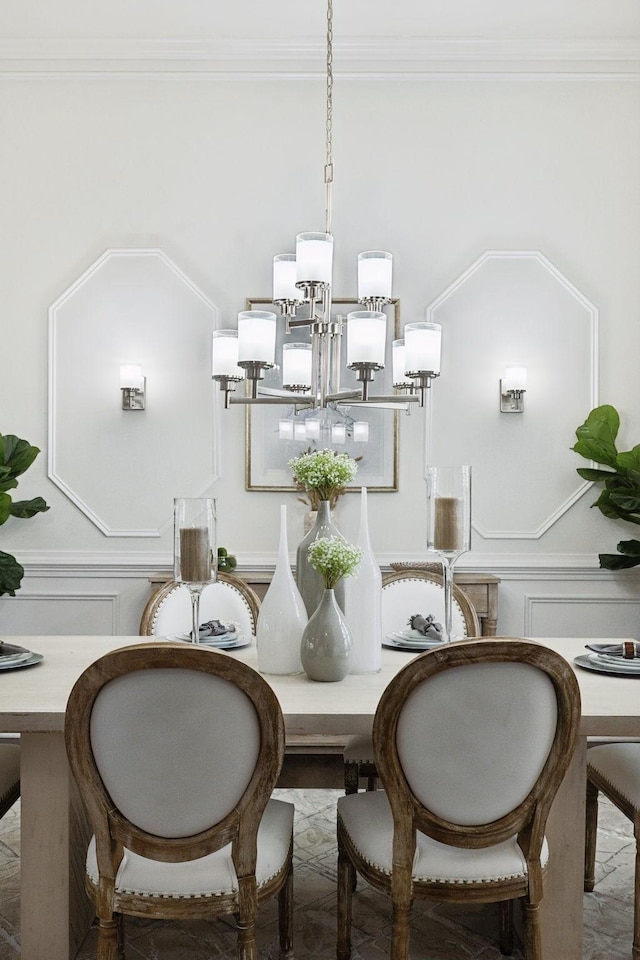 dining room featuring a wainscoted wall, ornamental molding, a decorative wall, and a notable chandelier