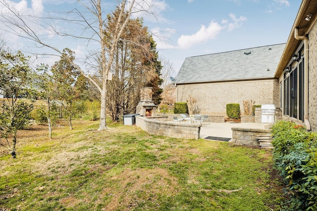 view of yard with an outdoor stone fireplace and a patio area