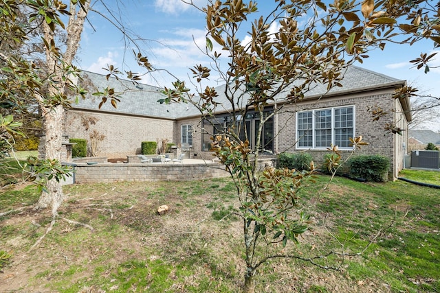 rear view of house with a patio area, a yard, brick siding, and central air condition unit