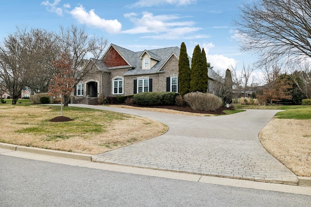 view of front facade with driveway, brick siding, and a front yard