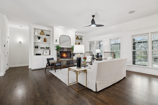 living room with a fireplace, a ceiling fan, baseboards, ornamental molding, and dark wood-style floors