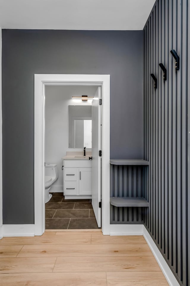 bathroom with wood tiled floor, baseboards, vanity, and toilet