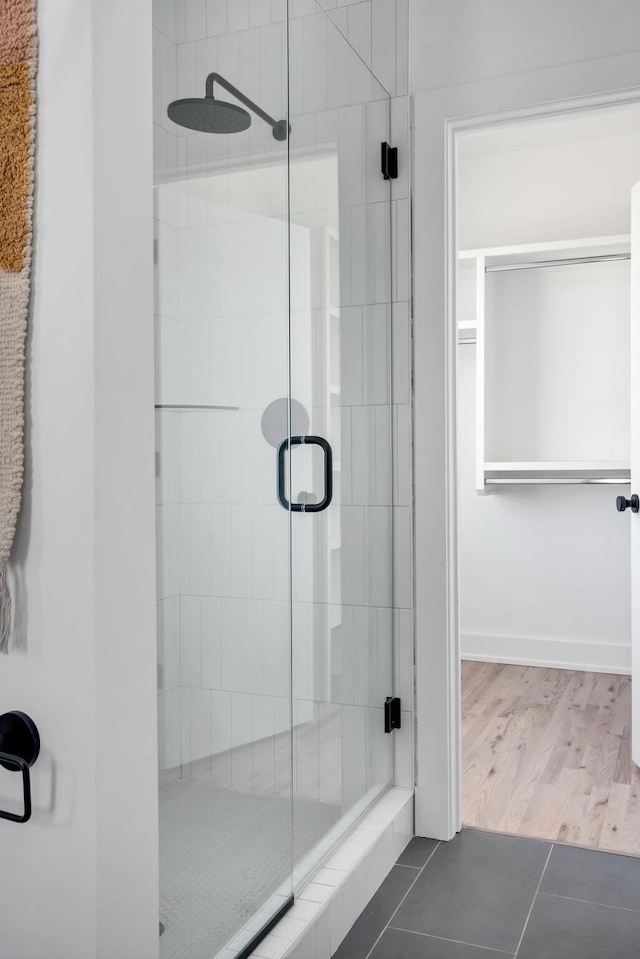 full bath featuring tile patterned flooring, a shower stall, and baseboards