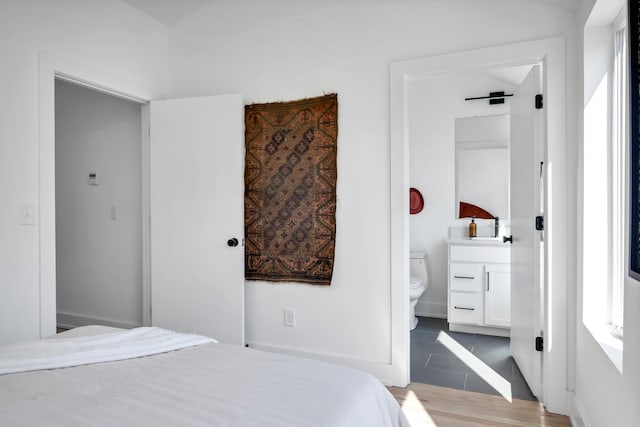 bedroom featuring wood finished floors and connected bathroom