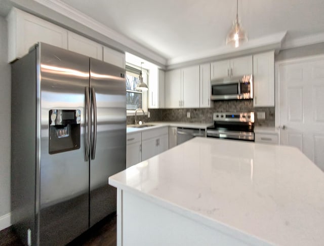 kitchen with decorative light fixtures, decorative backsplash, appliances with stainless steel finishes, white cabinets, and a sink