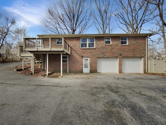 view of front of property featuring a garage, fence, aphalt driveway, and brick siding