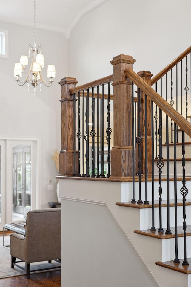 stairs with a chandelier, ornamental molding, wood finished floors, and a high ceiling