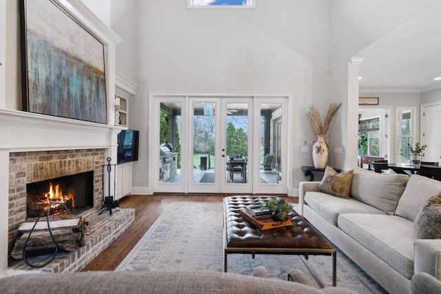 living area with baseboards, ornamental molding, wood finished floors, french doors, and a fireplace