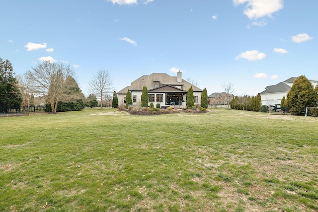 rear view of house featuring fence, a chimney, and a lawn