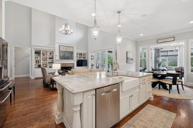 kitchen featuring dark wood-style floors, a fireplace, stainless steel dishwasher, a sink, and an island with sink