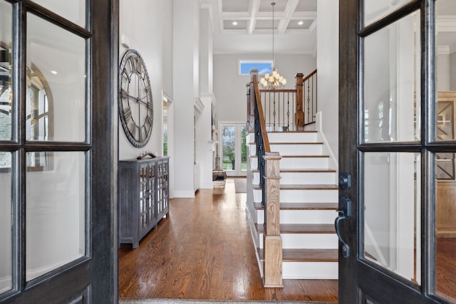 foyer with coffered ceiling, a towering ceiling, dark wood-style flooring, beamed ceiling, and stairs