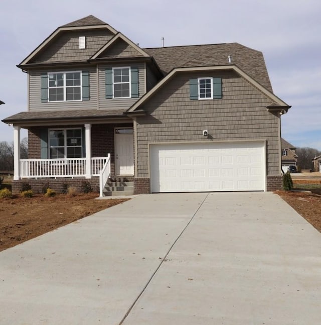 craftsman-style house featuring covered porch, concrete driveway, brick siding, and a garage