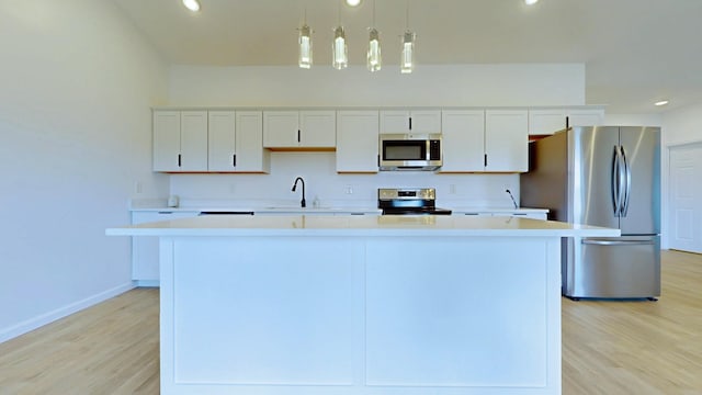 kitchen featuring white cabinetry, light countertops, a kitchen island, and stainless steel appliances