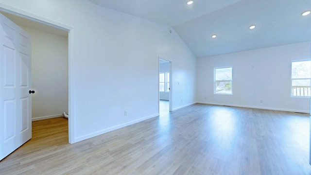 unfurnished room featuring vaulted ceiling, plenty of natural light, baseboards, and light wood-type flooring