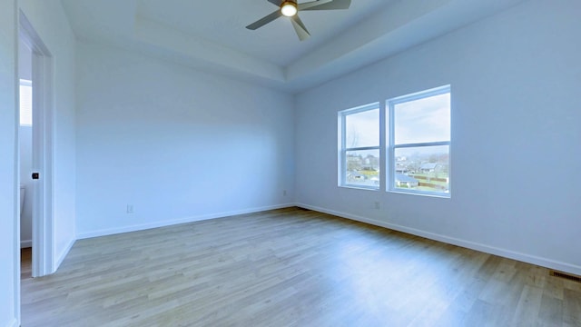 empty room with visible vents, baseboards, wood finished floors, and a ceiling fan