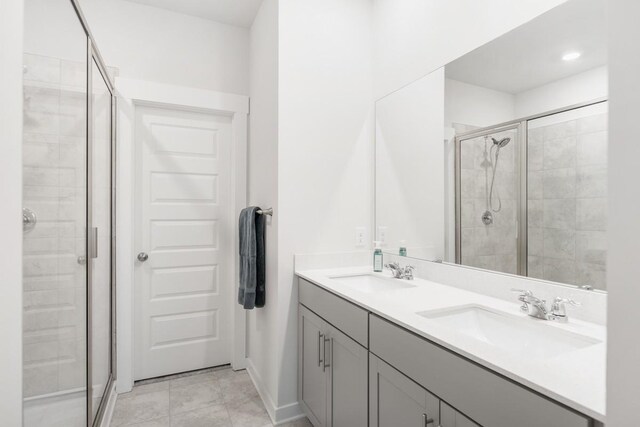 full bathroom with a stall shower, a sink, baseboards, and double vanity