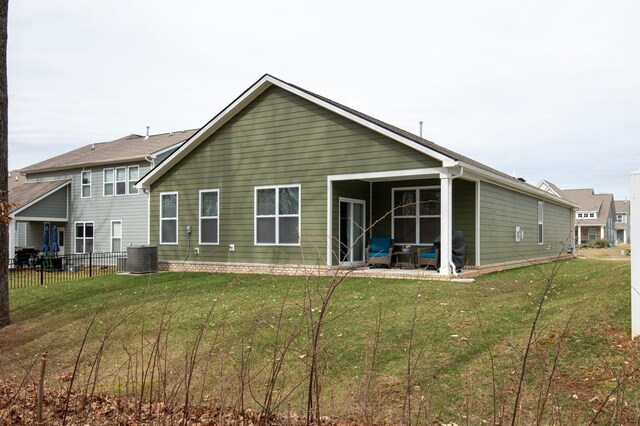 rear view of house with a lawn, central AC unit, and fence