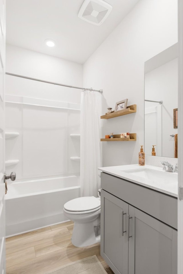 bathroom featuring shower / bath combination with curtain, vanity, toilet, and wood finished floors