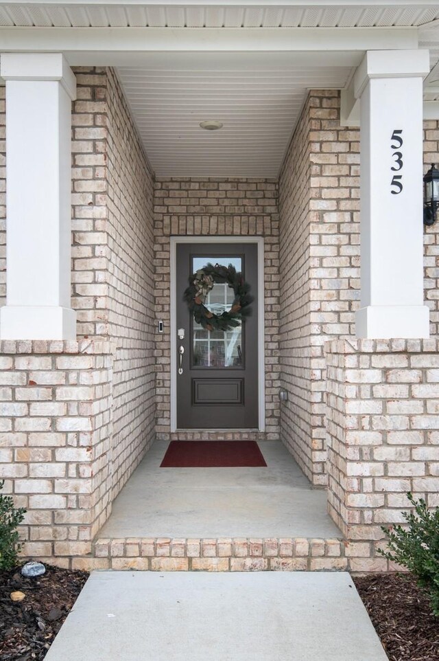 entrance to property featuring covered porch and brick siding