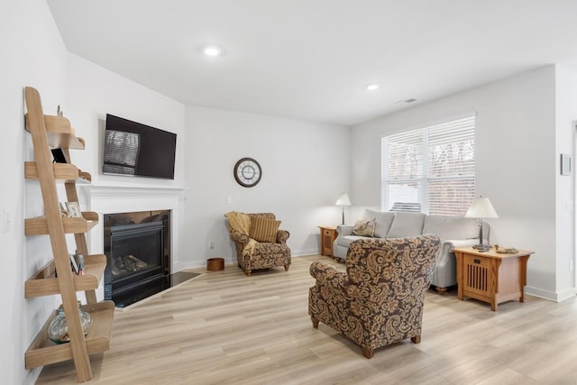 living area with light wood-style floors, a fireplace with flush hearth, baseboards, and recessed lighting