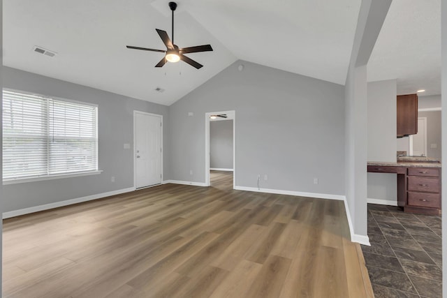 unfurnished living room featuring visible vents, dark wood-type flooring, a ceiling fan, high vaulted ceiling, and baseboards