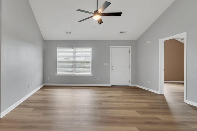 spare room with baseboards, visible vents, vaulted ceiling, and wood finished floors