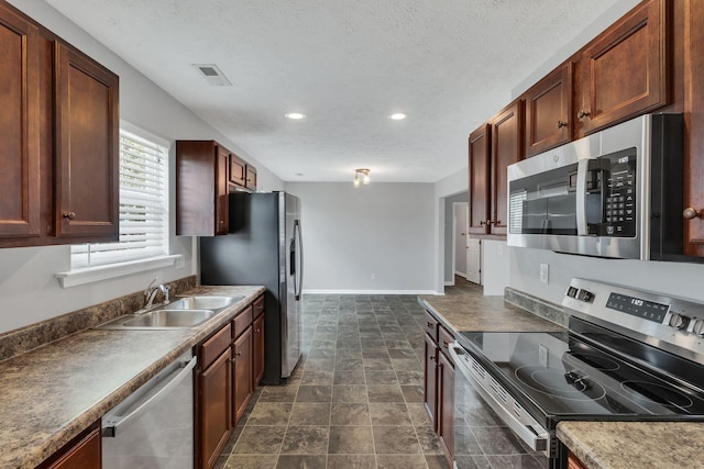 kitchen with a textured ceiling, a sink, visible vents, baseboards, and appliances with stainless steel finishes