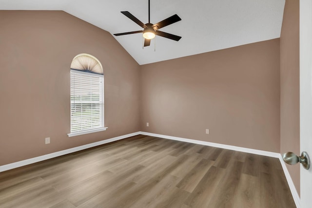 unfurnished room with a ceiling fan, baseboards, vaulted ceiling, and wood finished floors