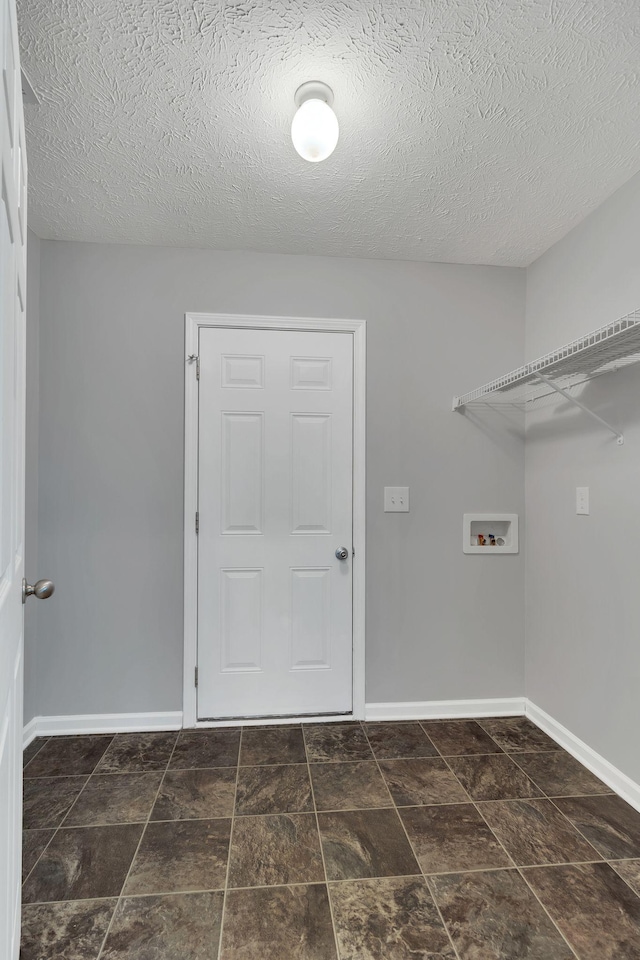 laundry room with a textured ceiling, laundry area, washer hookup, and baseboards