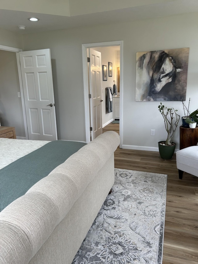 bedroom with connected bathroom, baseboards, wood finished floors, and recessed lighting