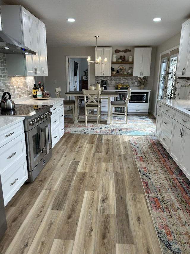 kitchen featuring open shelves, appliances with stainless steel finishes, white cabinets, light wood-type flooring, and wall chimney exhaust hood