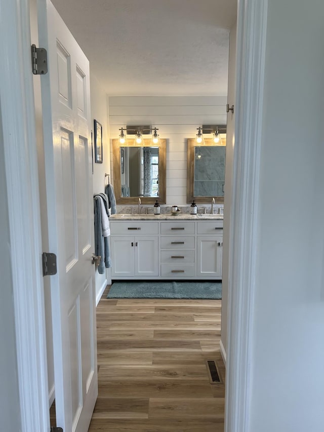 bathroom featuring a sink, double vanity, visible vents, and wood finished floors