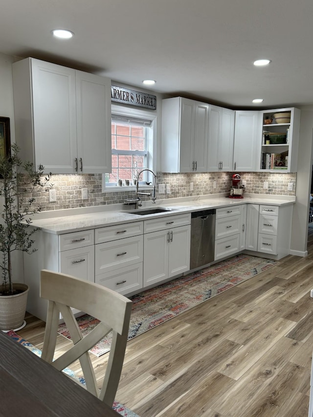 kitchen featuring dishwasher, light wood-type flooring, a sink, and white cabinets