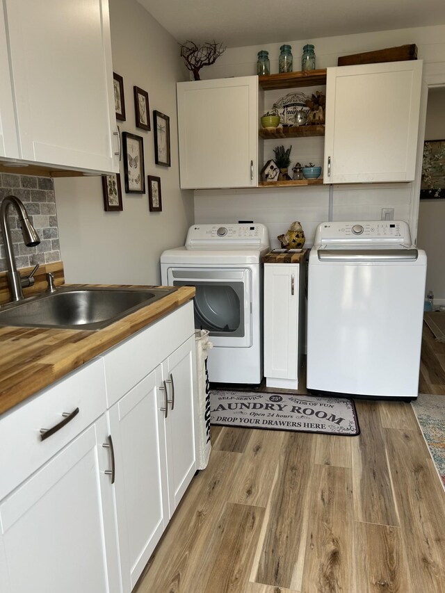 laundry room featuring light wood finished floors, a sink, cabinet space, and washer and dryer