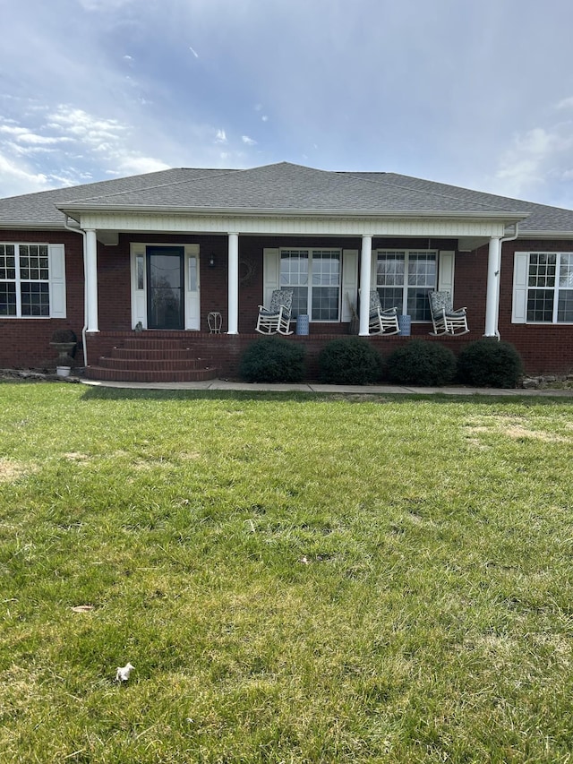 view of front of home with a front yard, covered porch, and brick siding