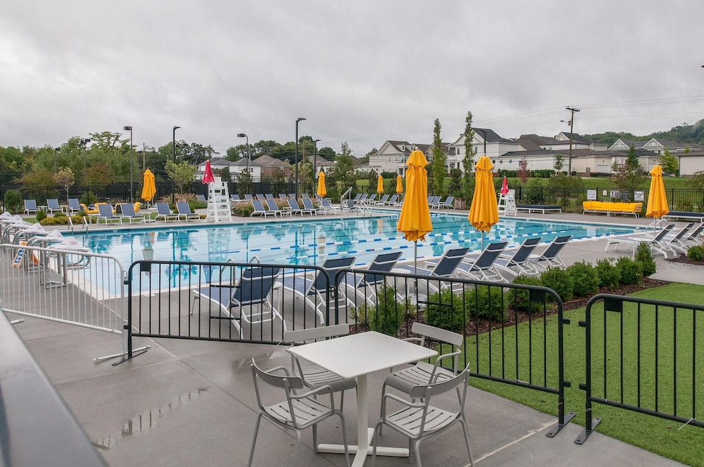 community pool with a patio area, fence, and a lawn