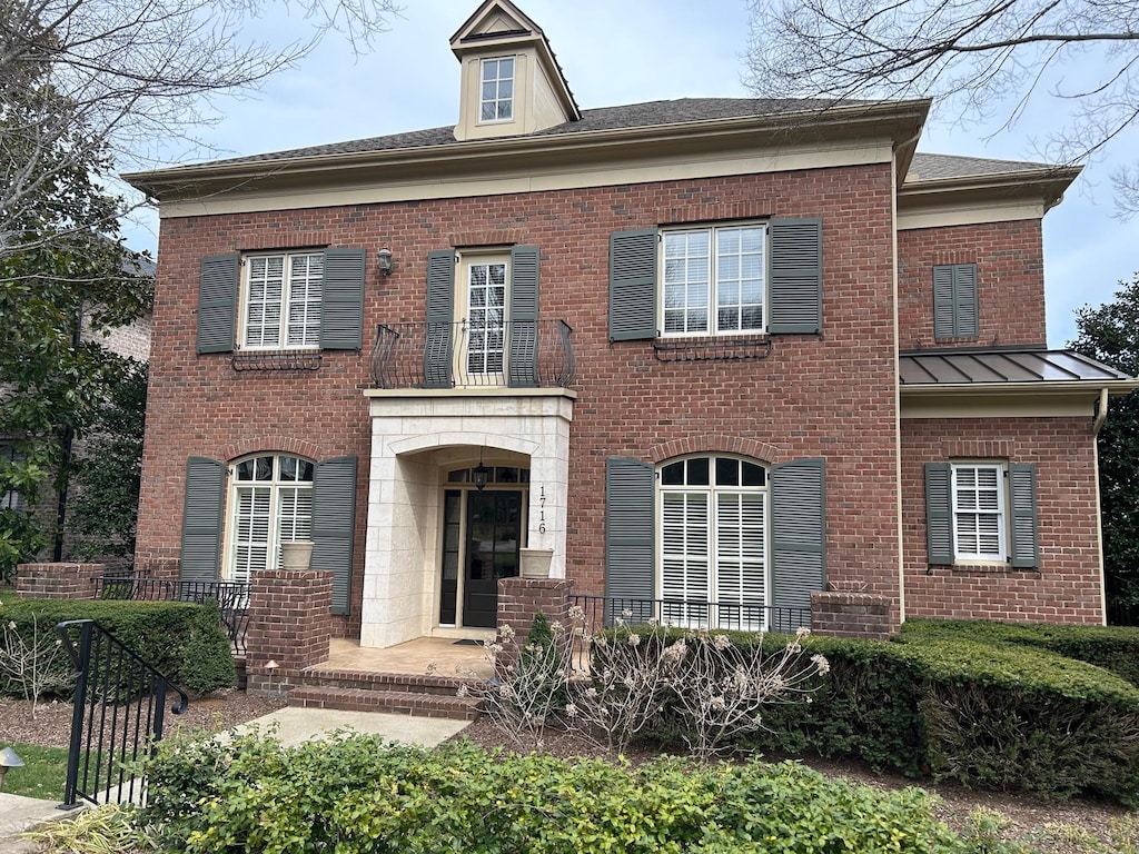 colonial inspired home with a standing seam roof, metal roof, covered porch, and brick siding