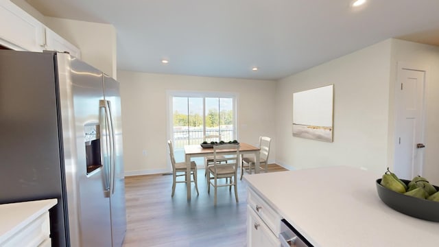 kitchen with white cabinets, light countertops, light wood-style flooring, and stainless steel fridge with ice dispenser