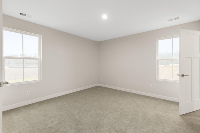 empty room with visible vents, light carpet, and baseboards