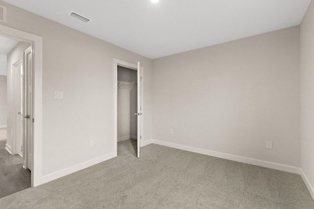 unfurnished bedroom with a closet, carpet, visible vents, and baseboards